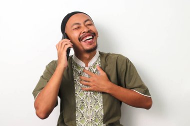 Koko 'daki mutlu Endonezyalı Müslüman adam ve Ramazan' da arkadaşlarıyla veya aileleriyle yaptığı hoş bir sohbet sırasında telefonuyla gülüyor ve gülümsüyor. Beyaz bir arkaplanda izole edilmiş