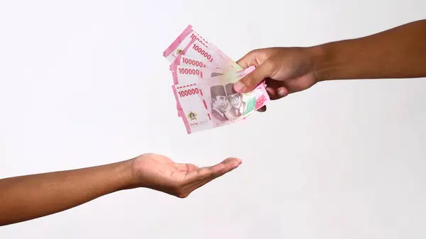 Stock image Hand holding a large amount of Indonesian Rupiah banknotes, isolated on white background. Ideal for investment, savings, donation, loans, and financial concepts