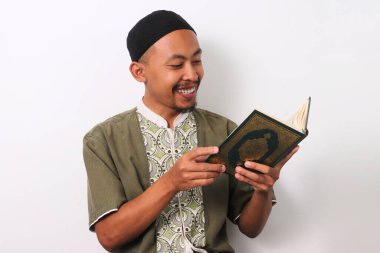 An Indonesian Muslim man reciting the Holy Quran with focus during Ramadan. Isolated on a white background clipart