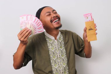 Endonezyalı Müslüman adam Endonezya Rupiah banknotlarıyla dolu kahverengi bir zarf tutuyor. Bu zarf Angpao Lebaran 'ı ya da Kurban Bayramı' nda verilen Ramazan Bayramı hediyesini temsil ediyor. Beyaz bir arkaplanda izole edilmiş