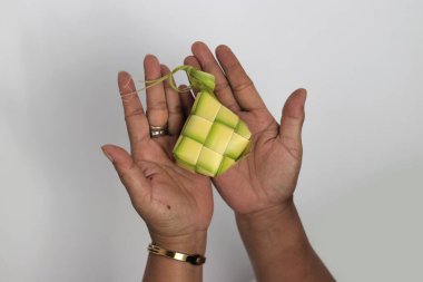 Ketupat kesesi, beyaz arka planda izole edilmiş genç hindistan cevizi yapraklarından (janur) örülmüş geleneksel bir Endonezya yemeği.