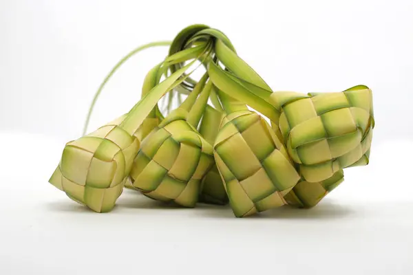 Multiple ketupat pouches (woven palm leaves), a traditional Indonesian dish, on white background