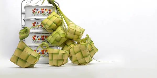 Multiple ketupat pouches (woven palm leaves) alongside a rantang (stacked Indonesian food container), on white background.