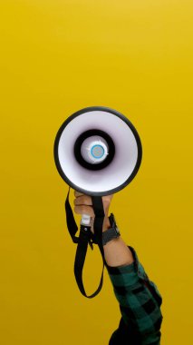 Hand Holding a Megaphone, Isolated on a Yellow Background clipart