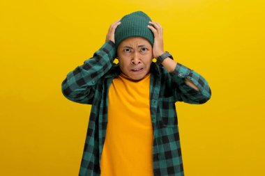 Asyalı endişeli genç bir adam, bereli bir şapka ve gündelik bir gömlek giymiş, paniklemiş ve kafasından yakalamış, görünür bir şekilde endişeli ve hayal kırıklığına uğramış. Kameraya ciddi bir başarısızlığın farkına vararak bakıyor..