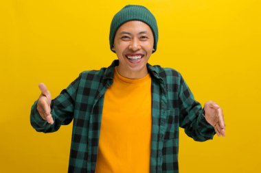 Sıradan kıyafetler giyen ve bereli şapka takan genç bir Asyalı el hareketleriyle, boyut ve ölçü kavramını aktarırken büyük ya da büyük beden ölçülerini gösteriyor.