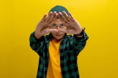 Sıradan bir gömlek giyen ve bere takan genç Asyalı adam elleriyle üçgen bir şekil yaratıyor. Çevre koruma, geri dönüşüm ve yeniden kullanım kavramını sembolize ediyor.