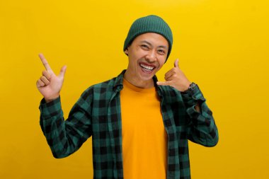 Hevesli Asyalı genç bir adam, bereli bir şapka ve sıradan bir gömlek giymiş, boş bir yeri işaret ederken beni çağırıyor, sarı bir arka fona karşı duruyor.