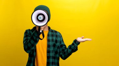 Mutlu Asyalı adam elini boş fotokopi alanında yana uzatıyor, indirimli bir tanıtım duyurusu yapıyor, özel bir teklif ya da satış, diğer elinde bir megafon tutarken. Sarı arka planda izole edilmiş.