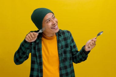 Şapka ve gündelik gömlek giyen hevesli Asyalı genç adam, sarı arka planda bir kaşık ve çatal tutarken onun yanındaki boş bir alanı hevesle işaret ediyor.