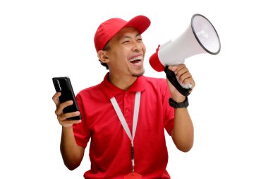 Kırmızı şapkalı ve polo tişörtlü heyecanlı bir Asyalı teslimatçı, beyaz arka planda izole edilmiş bir megafonu tutarken kameraya beyaz ekranlı bir telefon gösteriyor.