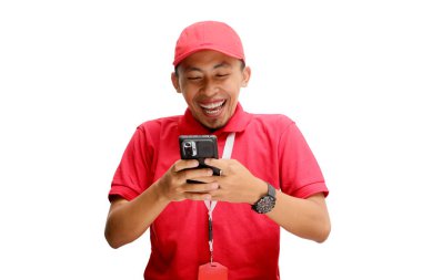 Heyecanlı Asyalı kurye ya da kurye, akıllı telefonundan sevinçle harika haberler okuyarak heyecan ve mutluluğu ifade ediyor. Beyaz bir arkaplanda izole edilmiş
