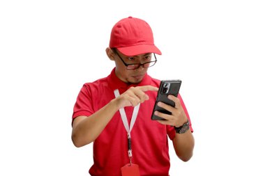 Asyalı kurye ya da kurye gözlüğünü ayarlıyor, telefonundan bir şeyler okuyor. Beyaz bir arkaplanda izole edilmiş