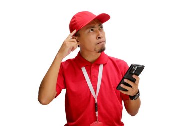 Düşünceli bir Asyalı kurye ya da kurye düşünceli bir jest yapıyor, elinde telefon tutarken bir şeyler düşünüyor. Beyaz bir arkaplanda izole edilmiş