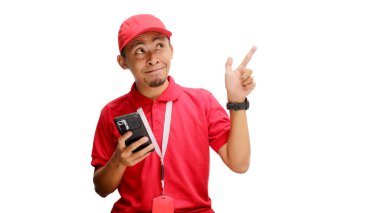 Heyecanlı Asyalı kurye ya da kurye, elinde telefon tutarken, indirim, özel teklif ya da büyük anlaşma gibi mesajlar için boş fotokopi alanını işaret ediyor. Beyaz bir arkaplanda izole edilmiş