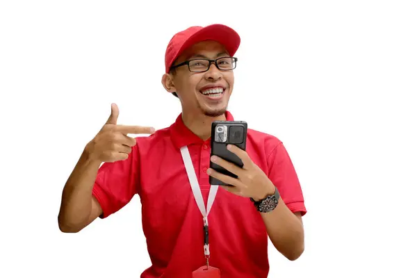 stock image Excited Asian delivery man wearing eyeglasses or courier pointing to a phone with an empty white screen display, featuring copy space, isolated on a white background