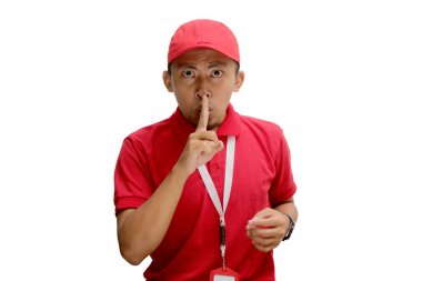Asyalı teslimatçı, parmaklarını dudaklarının üzerinde çaprazlayarak sessizlik işareti veriyor. Konuşmayı kesmesini ya da sınırlı özel teklif veya indirim konusunda sessiz kalmasını işaret ediyor. Beyaz arkaplanda izole