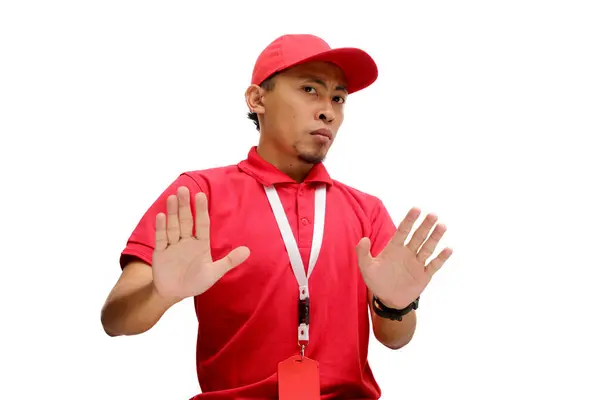 stock image Asian delivery man or courier is pulling his hands away with palms facing outward, expressing refusal and denial with a no thanks gesture, isolated on a white background.