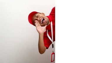 Asyalı kurye ya da kurye, beyaz bir duvarın arkasından heyecanlı bir şekilde bağırıyor ve önemli bir duyuru yapıyor. Express dağıtım hizmetleri, özel teklifler ve e-ticaret duyuruları kavramı