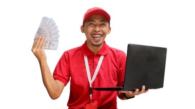 Asyalı kurye, elinde para tutarken beyaz arka planda dizüstü bilgisayar kullanıyor. Profesyonellik, e-ticaret yönetimi, mali işlemler, dağıtım hizmetleri ve iş verimliliği kavramı