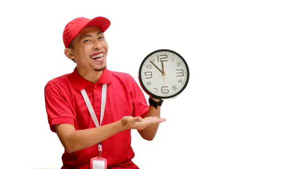 stock image Excited Asian delivery man or courier confidently presents a clock to the camera, isolated on a white background.