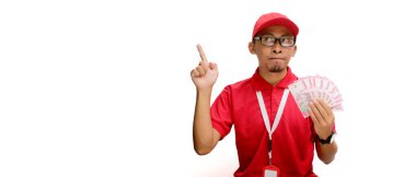 Heyecanlı Asyalı kurye ya da kurye, beyaz bir arkaplan karşısında para banknotları tutarken, metin ya da reklam için boş fotokopi alanına heyecanlı bir şekilde işaret ediyor.