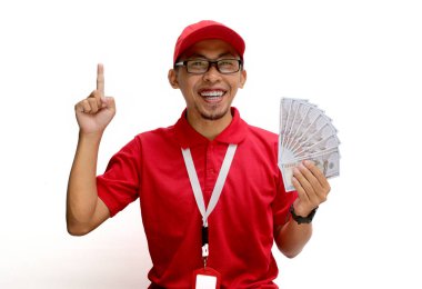 Heyecanlı Asyalı kurye ya da kurye, beyaz bir arkaplan karşısında para banknotları tutarken, metin ya da reklam için boş fotokopi alanına heyecanlı bir şekilde işaret ediyor.