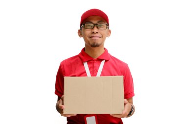 Mutlu Asyalı kurye ya da kurye elinde karton bir paket tutuyor ve kameraya gülümsüyor. Beyaz arka planda izole edilmiş, teslimat hizmetlerinde tatmin ve verimlilik kavramı