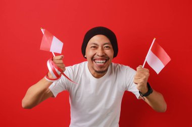 Endonezya 'nın elinde Endonezya bayrağı bulunan destekçisi, 17 Ağustos' taki Endonezya Bağımsızlık Günü 'nde milli takımın başarısını ve zaferini kırmızı arka planda kutlayarak sevinçle yumruğunu kaldırdı.