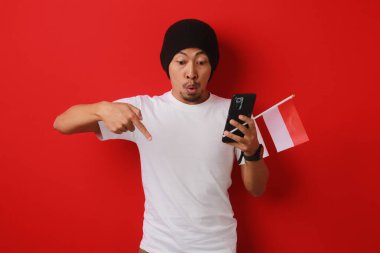 Endonezya Bağımsızlık Günü kutlamaları sırasında 17 Ağustos 'ta elinde Endonezya bayrağı ve telefonu tutarken beyaz tişörtlü bir adam boş fotokopi alanını işaret ediyor.