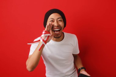 Endonezya Bağımsızlık Günü tanıtım etkinliği sırasında elinde telefonla bağıran, özel teklifler, indirimler ve büyük anlaşmalar sunan heyecanlı Endonezyalı genç adam, beyaz bir arka planda izole edildi.