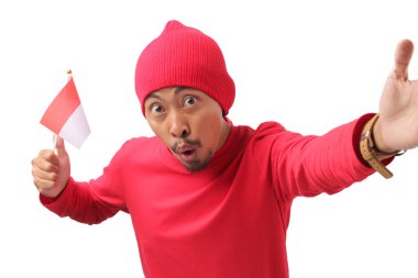 17 Ağustos 'ta Endonezya Bağımsızlık Günü' nü kutlarken ve beyaz arka planda izole edilmiş Endonezya bayrağını tutarken uzun kollu kırmızı bir gömlek ve bereli bir şapkayla selfie çekiyor.