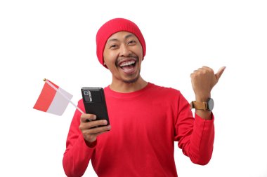 Endonezya Bağımsızlık Günü kutlamaları sırasında elinde Endonezya bayrağı ve telefonu tutarken, Endonezya 'nın kırmızı uzun kollu gömleği boş fotokopi alanını işaret ediyor. 17 Ağustos' ta beyaz arka planda izole edilmiş.