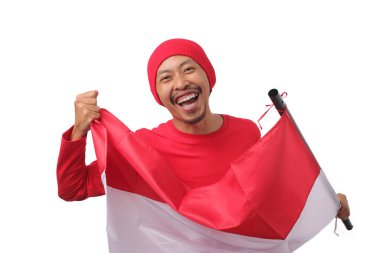 Endonezya Bağımsızlık Günü 'nü kutlamak için 17 Ağustos' ta kırmızı uzun kollu tişört ve kırmızı şapka giyen mutlu Endonezyalı adam Endonezya bayrağını taşıyor. Beyaz bir arkaplanda izole edilmiş.