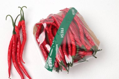 Fresh curly red chili peppers (Cabai Merah Keriting), packed in a plastic container with a cardboard base are ready to sell in a grocery display. The package is labeled 