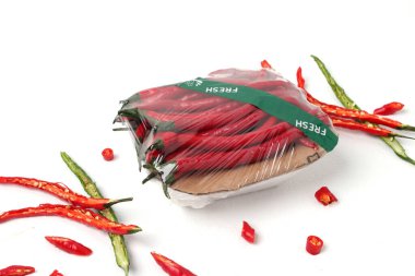 Fresh curly red chili peppers (Cabai Merah Keriting), packed in a plastic container with a cardboard base are ready to sell in a grocery display. The package is labeled 