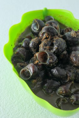 Baharatlı sosta pişmiş nehir salyangozlarıyla dolu bir kase. Tutut, Endonezya 'nın bazı bölgelerinde tatlı su salyangozlarından yapılan popüler bir yemektir..
