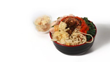 Bir kase Mie Ayam, tipik bir Endonezya yemeği, tavuklu erişte, doğranmış tavuk, köfte, köfte, yeşil sebze ve çeşitli malzemeler, beyaz bir arka planda izole edilmiş.