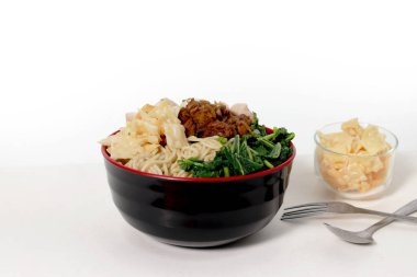 Bir kase Mie Ayam, tipik bir Endonezya yemeği, tavuklu erişte, doğranmış tavuk, köfte, köfte, yeşil sebze ve çeşitli malzemeler, beyaz bir arka planda izole edilmiş.