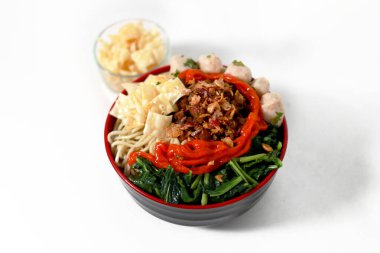 Bir kase Mie Ayam, tipik bir Endonezya yemeği, tavuklu erişte, doğranmış tavuk, köfte, köfte, yeşil sebze ve çeşitli malzemeler, beyaz bir arka planda izole edilmiş.