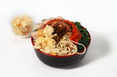 Bir kase Mie Ayam, tipik bir Endonezya yemeği, tavuklu erişte, doğranmış tavuk, köfte, köfte, yeşil sebze ve çeşitli malzemeler, beyaz bir arka planda izole edilmiş.