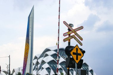 Bandung, West Java, Indonesia - October 04, 2024: Street crossing a railway track in front of the Al Jabbar Mosque area, with traffic signals and barriers to control the crossing clipart