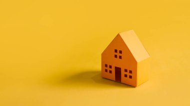 Turuncu arka planda geniş bir kopya alanı olan canlı bir turuncu kağıt ev modeli.