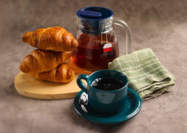 Sıcak bir fincan çay ve taze pişmiş kruvasanla sıcak bir kahvaltı.