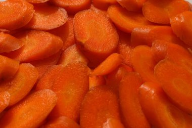 Canlı turuncu bir zemin oluşturan taze havuç dilimlerinden oluşan tam kare yakın plan.