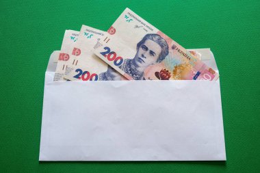 200 Ukrayna hrivniası yeşil arka planda beyaz bir zarfın içinde. Yüksek kalite fotoğraf