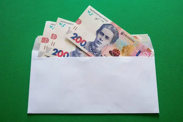 stock image 200 Ukrainian hryvnias in a white envelope on a green background. High quality photo