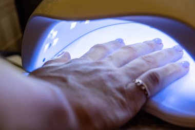 Polimerizasyon prosedürü, el tırnaklarına uygulanan cila kurutma, kuaförde, evde yapılan manikür. Yüksek kalite fotoğraf
