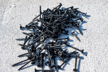 Yakın plan vidalar, metal vidalar, demir vidalar, beyaz gözenekli betonda siyah vidalar, arka plan. Yüksek kalite fotoğraf