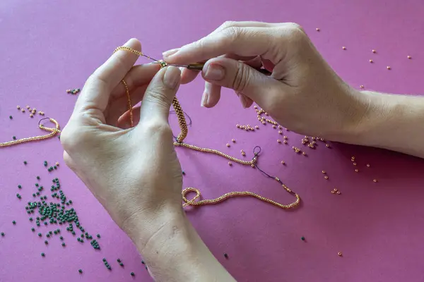 making a homemade bracelet from beads by the hands of a master girl close-up. High quality photo